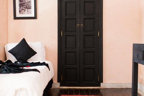 a bedroom with a black door and a white bed at Dar Sohane in Marrakesh