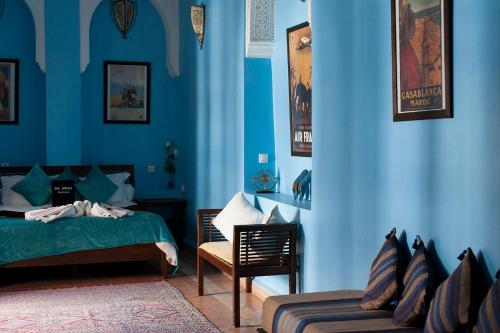 a bedroom with blue walls and a bed and a chair at Dar Sohane in Marrakesh