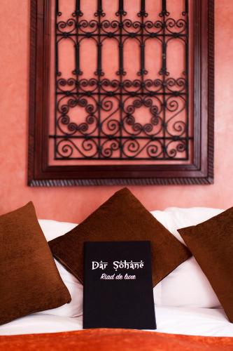 a sign sitting on top of a bed with brown pillows at Dar Sohane in Marrakesh