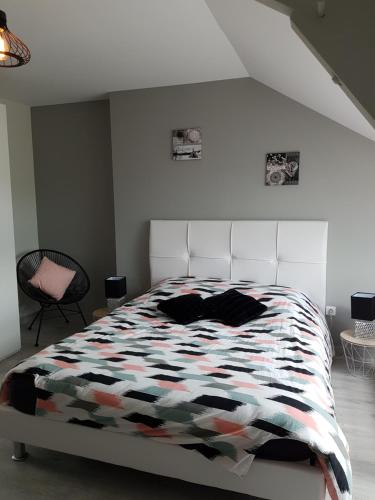 a white bedroom with a bed with a colorful comforter at Chez Onna in Theneuil