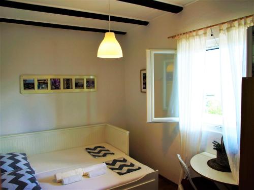 Schlafzimmer mit einem Bett, einem Tisch und einem Fenster in der Unterkunft Apartment Maslina in Premuda