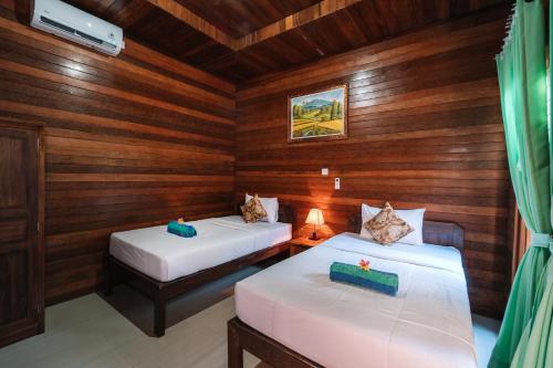 due letti in una stanza con pareti in legno di D and B Bungalow's by DeWizZ Management a Nusa Lembongan