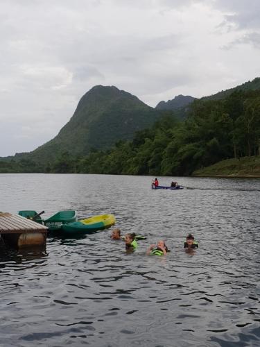 a group of people swimming in a lake with boats at Baan Krupong in Ban Tha Thong Mon