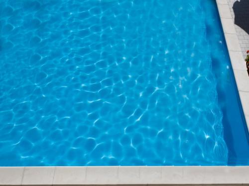 a swimming pool with blue water at Hotel Savoy in Pesaro