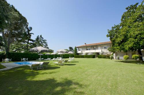 a lawn with chairs and a building and a pool at Hotel Venezia Park in Colà di Lazise
