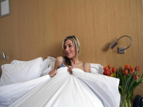 a woman sitting on a bed holding a dress at Mitico Hotel & Natural Spa in Bologna