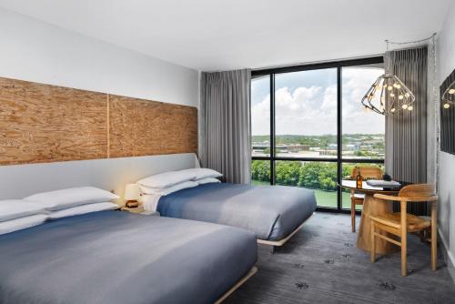 a hotel room with two beds and a desk and a table at The LINE Austin in Austin