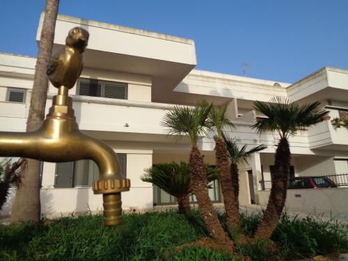 a gold fountain in front of a building with palm trees at B&B dei Ciclopi in Salice Salentino