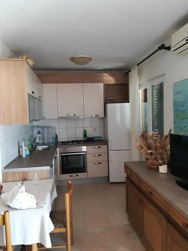 a kitchen with white cabinets and a table and a table and a dining room at Apartman JURJEVIĆ in Barić Draga