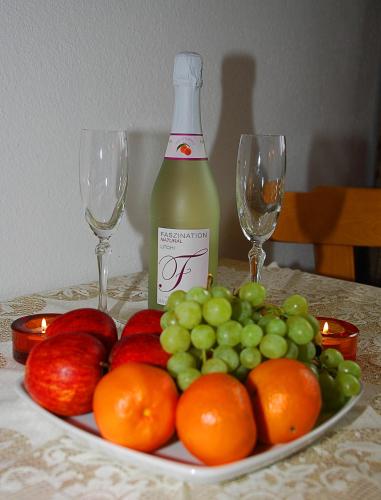 a plate of fruit with a bottle of wine and two glasses at Garni Samnaun in Kappl