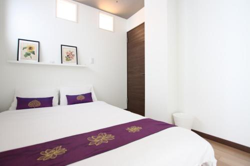 a bedroom with a white bed with purple sheets at Forest Terrace Tenjinminami in Fukuoka