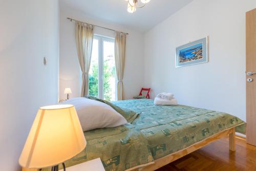 1 dormitorio con 1 cama con lámpara y ventana en Apartment with terrace and mini pool Green Gold, en Dubrovnik