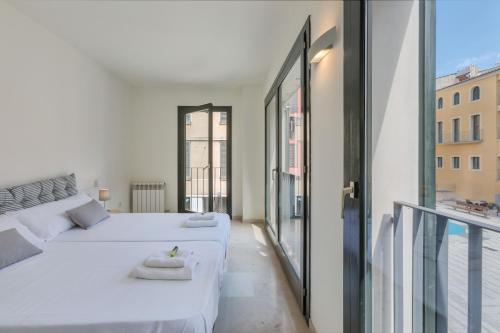 ジローナにあるFlateli Pou Rodó 1のベッドルーム1室(ベッド2台付)、バルコニーが備わります。