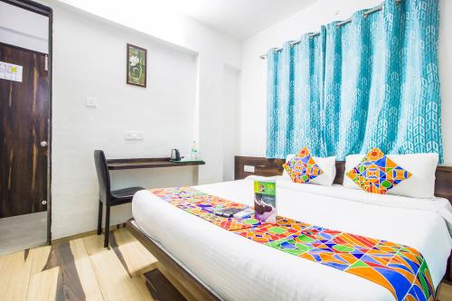 a bedroom with a bed and a blue curtain at FabHotel Pruthamesh Pride in Nashik