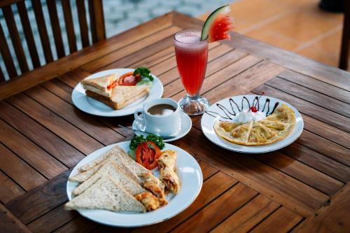 ein Holztisch mit Tellern mit Essen und einem Getränk in der Unterkunft D and B Bungalow's by DeWizZ Management in Nusa Lembongan