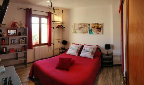 a bedroom with a red bed and a window at L'Oustalet in Sisteron