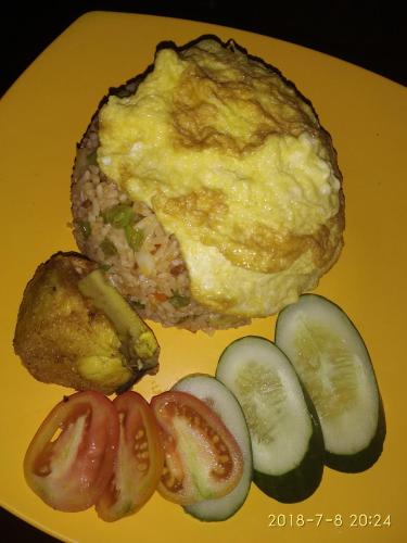 Ein Teller mit Essen, bestehend aus einem Omelett, einem Muffin und etwas Gemüse. in der Unterkunft Blue Mountain Cottage in Senaru