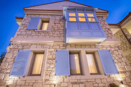 a stone building with blue shutters on it at Bademli Konak Otel in Datca