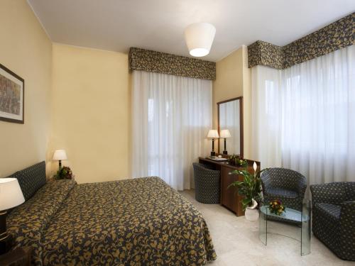 ein Hotelzimmer mit einem Bett, einem Tisch und Stühlen in der Unterkunft Hotel Savoy in Pesaro