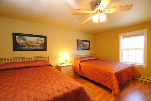 a bedroom with two beds and a ceiling fan at Keltic Quay Cottages & Bayfront Lodge in Whycocomagh
