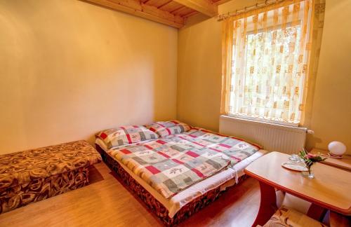 a bedroom with a bed and a table and a window at Penzión Janega in Liptovský Mikuláš