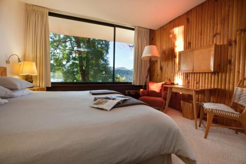 um quarto de hotel com uma cama e uma janela grande em Hotel Antumalal em Pucón