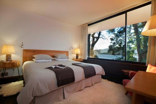 a bedroom with a large bed with a large window at Hotel Antumalal in Pucón