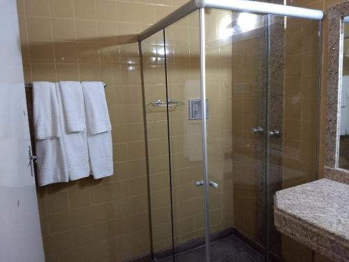 a shower with glass doors and towels in a bathroom at Hotel Tijuco Turismo in Diamantina