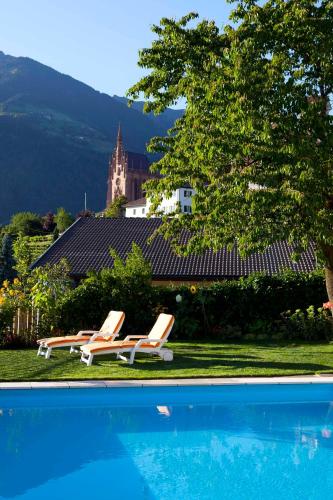 a group of lounge chairs next to a swimming pool at Hotel-Garni Appartement Gartenheim in Schenna