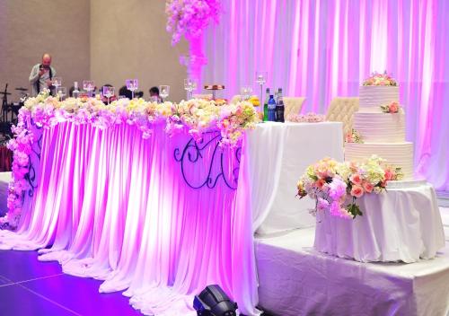 a table with a wedding cake and flowers on it at Euphoria Batumi Convention & Casino Hotel in Batumi