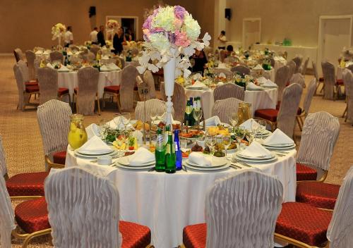a dining room with tables and chairs with food and flowers at Euphoria Batumi Convention & Casino Hotel in Batumi