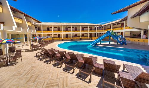 a resort pool with chairs and a slide at Porto Cálem Praia Hotel in Porto Seguro