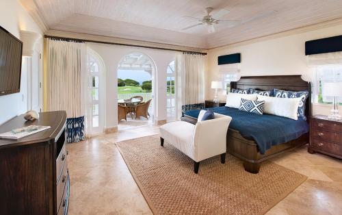 a bedroom with a bed and a chair and a table at Howzat! by Island Villas in Saint James