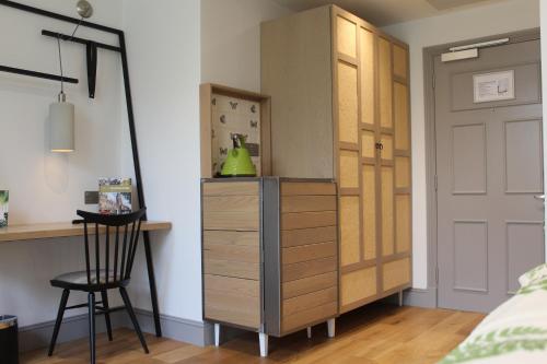 a bedroom with a dresser and a desk next to a door at The Gardens Hotel in Manchester