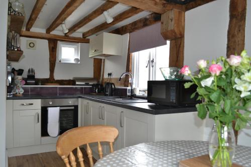 a kitchen with a table with a vase of flowers at Little Drift in Edgton