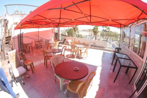 a patio with tables and chairs under a red umbrella at Palm Hostel in Jerusalem