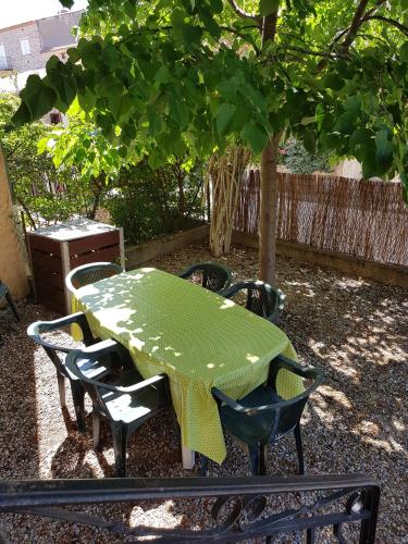 a green table and chairs in a yard with a tree at Maison les Salles-sur-Verdon in Les Salles-sur-Verdon