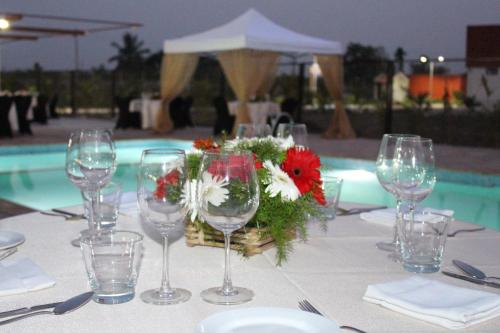 a table with wine glasses and a basket of flowers at Pride Elite, Phaltan in Phaltan