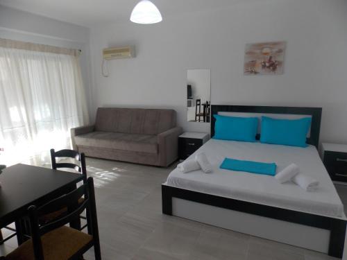 Un dormitorio con una cama, un sofá y una mesa. en Elvin Apartments, en Sarandë