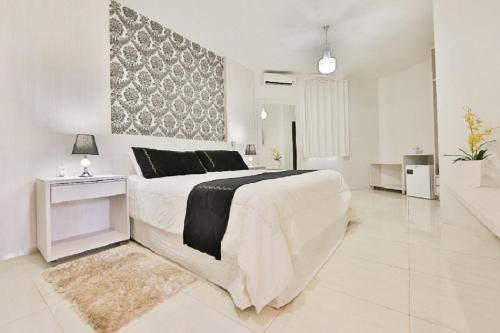 a white bedroom with a large bed and a rug at Olinda Hotel e Eventos in Toledo