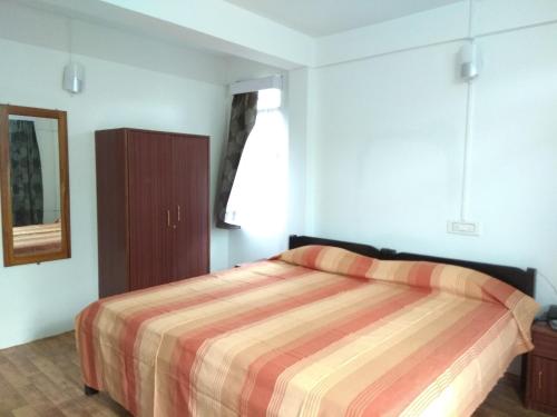 1 dormitorio con 1 cama con edredón a rayas en Latei Ville Inn en Shillong