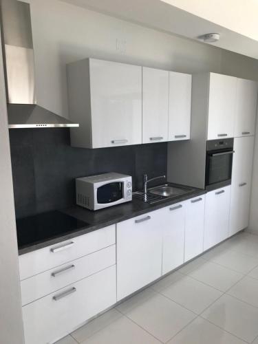 a kitchen with white cabinets and a sink and a microwave at Bakovic in Funtana