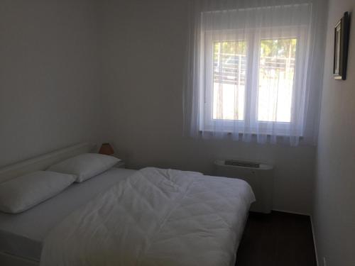 a bedroom with a white bed and a window at Bakovic in Funtana