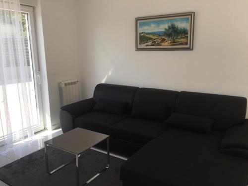 un soggiorno con divano nero e tavolo di Bakovic a Funtana
