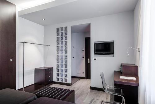 ein Wohnzimmer mit einem Sofa, einem Schreibtisch und einem TV in der Unterkunft Hotel Montebello in Montecatini Terme
