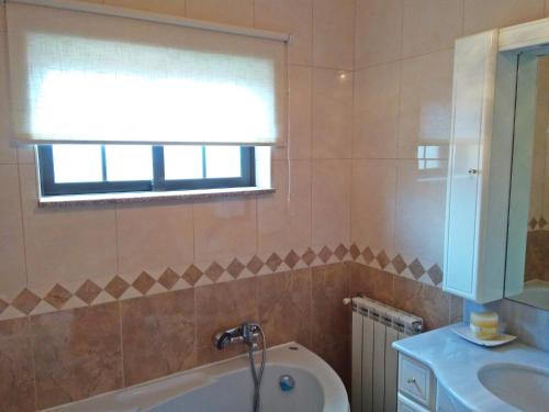 ein Badezimmer mit Badewanne und Waschbecken und einem Fenster in der Unterkunft Casa de Barreiros in Braga