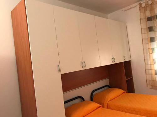 a small room with white cabinets and two beds at Appartamenti Alessio in Girasole