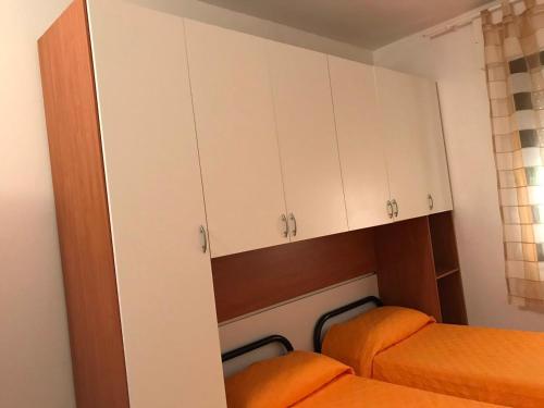 ジラソーレにあるAppartamenti Alessioの白いキャビネットとベッド2台が備わる小さな客室です。