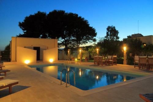 a swimming pool at night with a table and chairs at Masseria Li Campi in Cavallino di Lecce