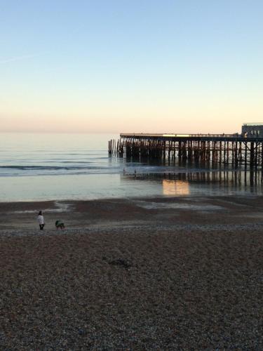 a person walking on the beach near a pier at Large Sunny King-Size En-Suite in Hastings